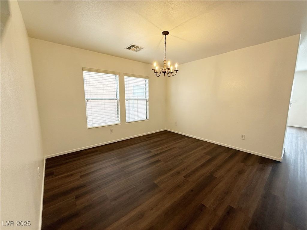 6228 Mercer Valley Street North Las Vegas, NV 89081 - Photo 6 of 41 Unfurnished room with dark wood-style flooring, a chandelier, and a textured ceiling