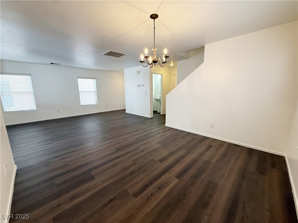6228 Mercer Valley Street North Las Vegas, NV 89081 - Photo 8 of 41 Unfurnished living room featuring dark wood-style flooring, a chandelier, and a textured ceiling