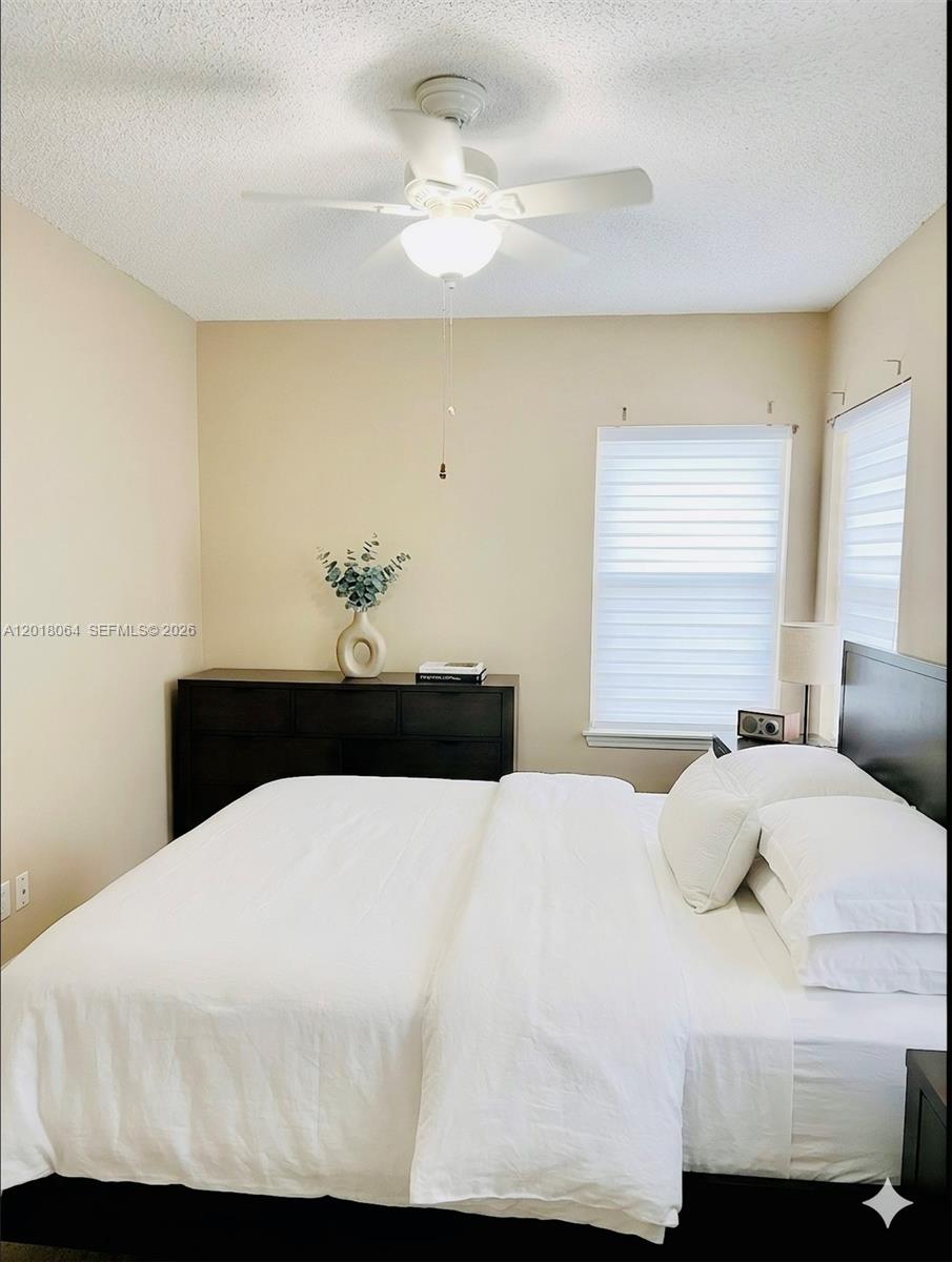 16213 Emerald Cove Road Weston, FL 33331 - Photo 14 of 27 a bedroom with a white bed and chandelier