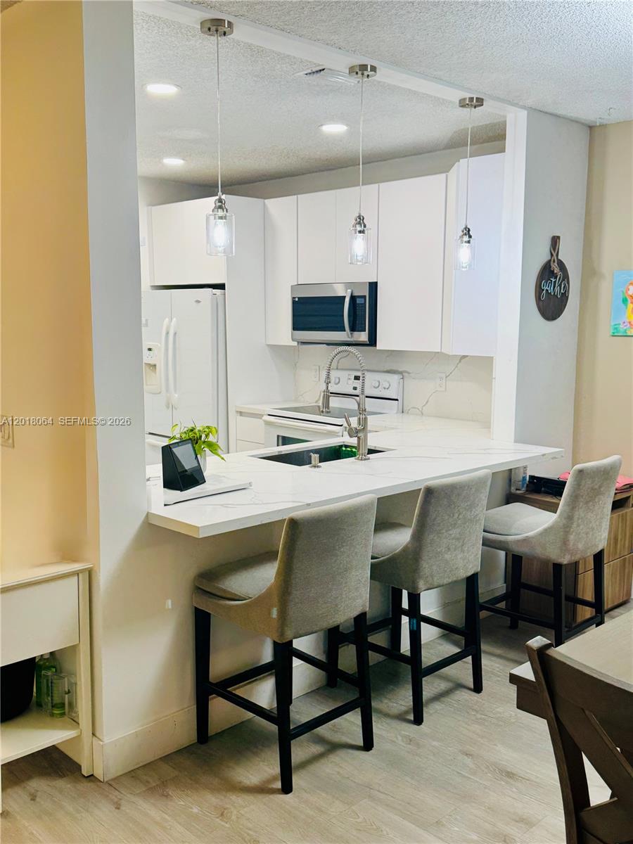 16213 Emerald Cove Road Weston, FL 33331 - Photo 3 of 27 a kitchen with stainless steel appliances kitchen island granite countertop a table chairs and a refrigerator