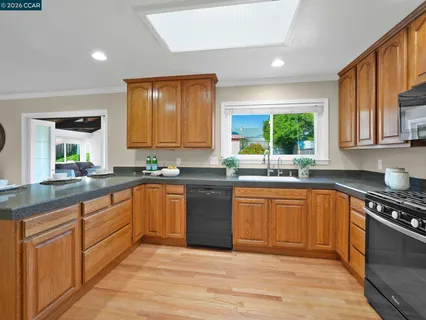 a kitchen with stainless steel appliances granite countertop wooden cabinets a stove a sink and a window