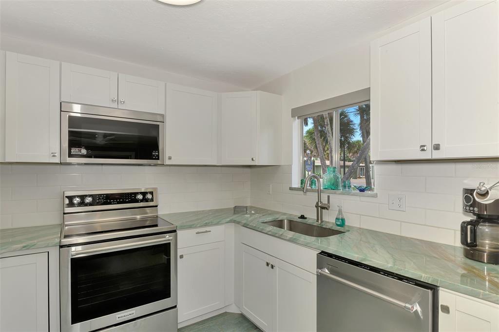 2985 North Beach Road, Unit C53 Englewood, FL 34223 - Photo 13 of 67 a kitchen with granite countertop a sink dishwasher a stove and a microwave oven with cabinets