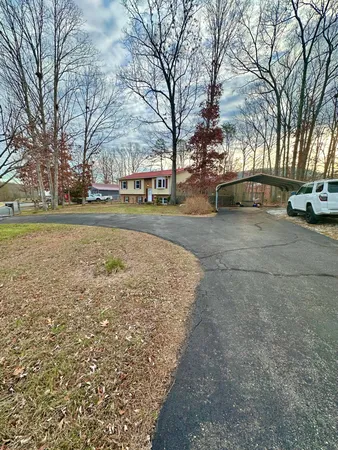 a view of a house with a yard and large trees