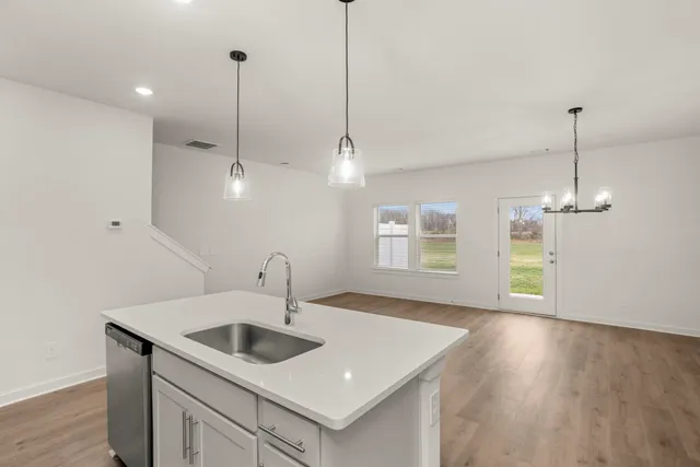 a kitchen with a sink chandelier and wooden floor
