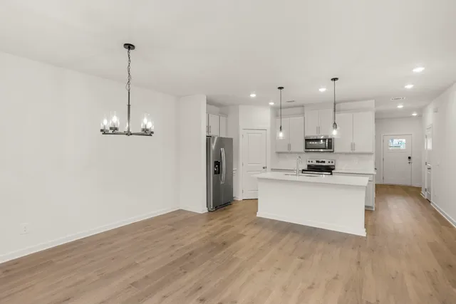 a view of a kitchen with stainless steel appliances granite countertop a refrigerator a stove top oven a sink and a wooden floor