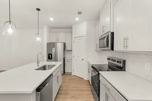 a kitchen with stainless steel appliances granite countertop a sink a stove and a refrigerator