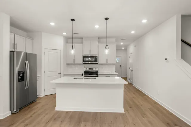 a kitchen with kitchen island a refrigerator a sink and wooden floor
