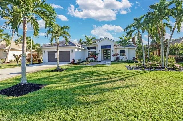 a view of a house with a big yard and palm trees