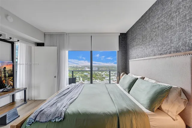 a bedroom with a bed window and a flat screen tv