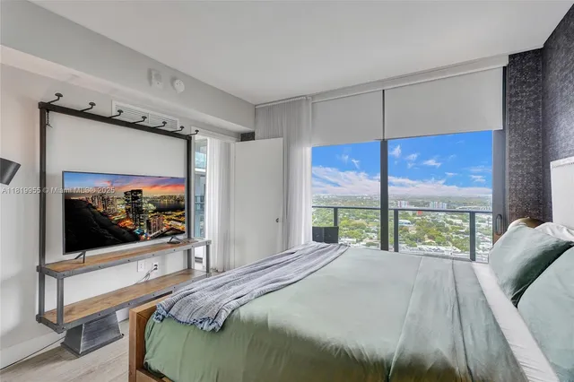 a bedroom with a large window and a flat screen tv