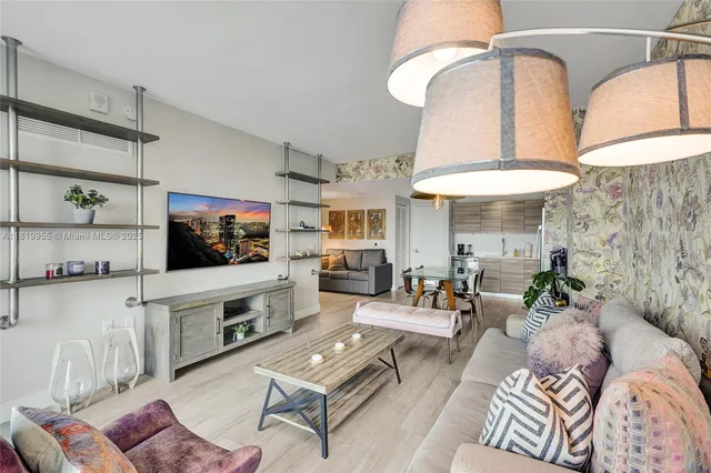 a living room with furniture a flat screen tv and kitchen view