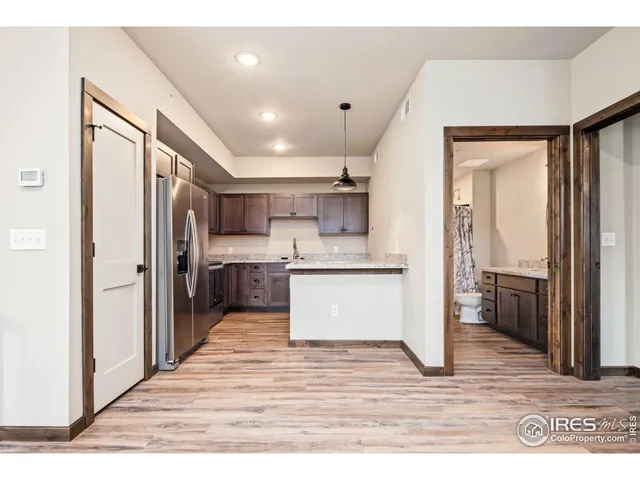 a room with stainless steel appliances kitchen island granite countertop a refrigerator and a sink