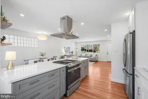 a kitchen with stainless steel appliances granite countertop a refrigerator sink and white cabinets with wooden floor