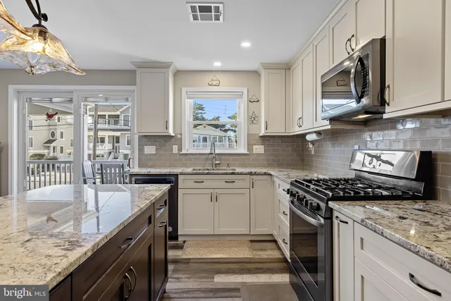 a kitchen with stainless steel appliances granite countertop a stove a sink and a microwave