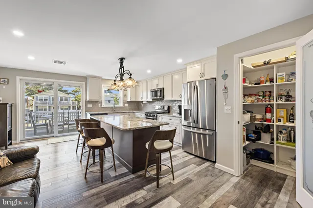 a kitchen with stainless steel appliances a dining table chairs and refrigerator