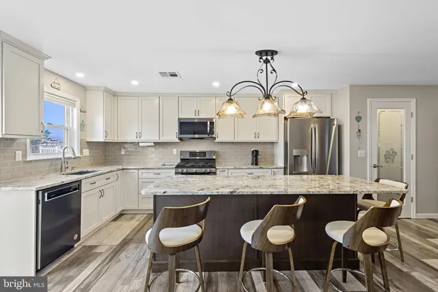 a kitchen with granite countertop a sink cabinets and stainless steel appliances