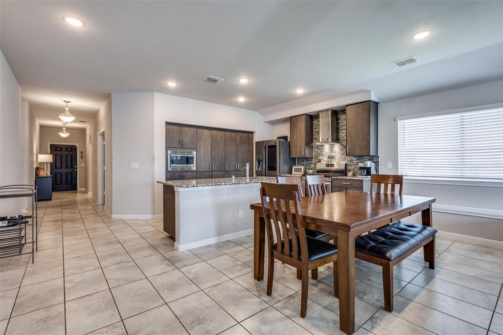 1404 Rosebush Road Aubrey, TX 76227 - Photo 11 of 25 a kitchen with stainless steel appliances granite countertop a sink a stove a dining table and chairs