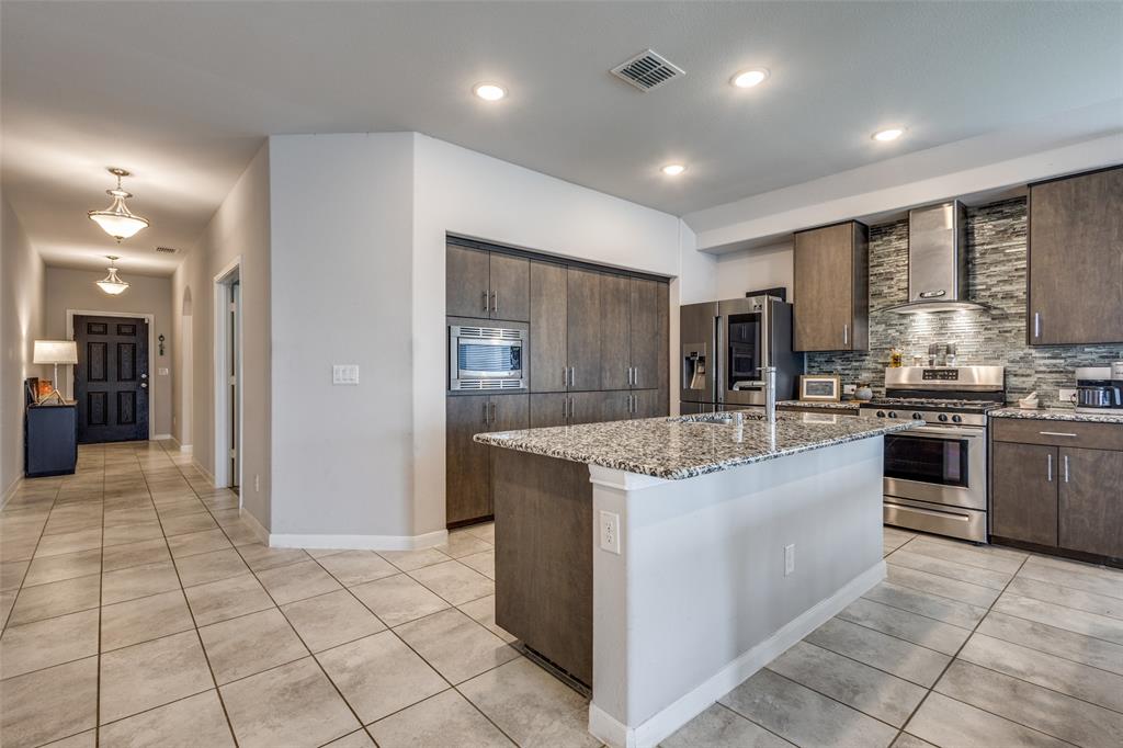 1404 Rosebush Road Aubrey, TX 76227 - Photo 7 of 25 a kitchen with stainless steel appliances granite countertop a stove and a refrigerator