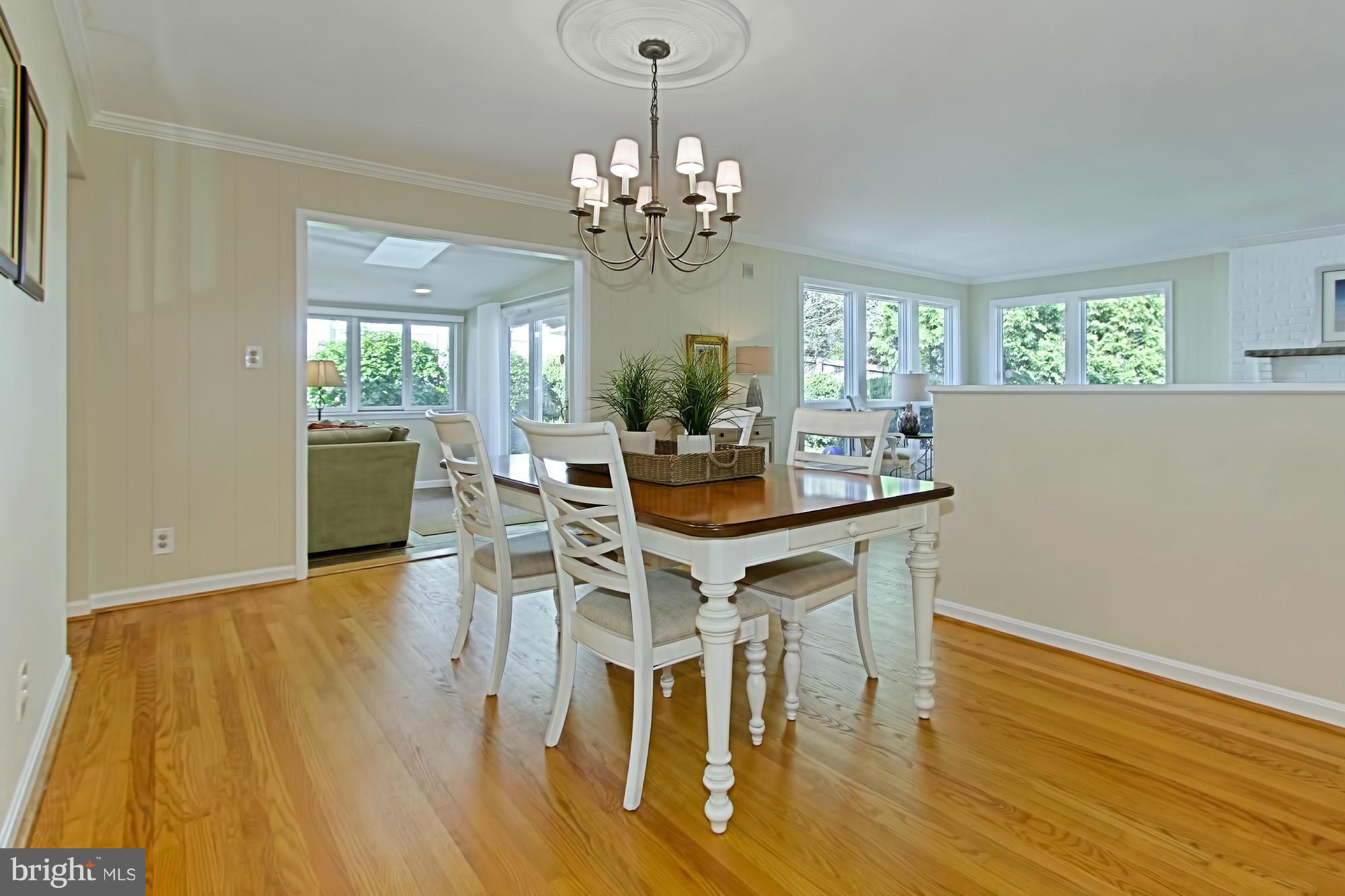 3900 Chesterbrook Road Arlington, VA 22207 - Photo 7 of 30 a dining room with wooden floor a chandelier a wooden table and chairs