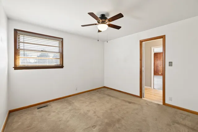an empty room with a window and a ceiling fan