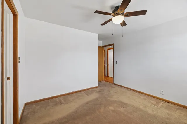 an empty room with closet and a chandelier fan