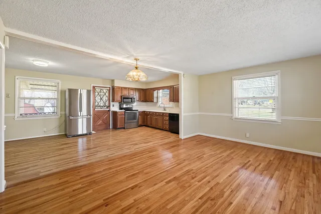 an empty room with wooden floor and chandelier