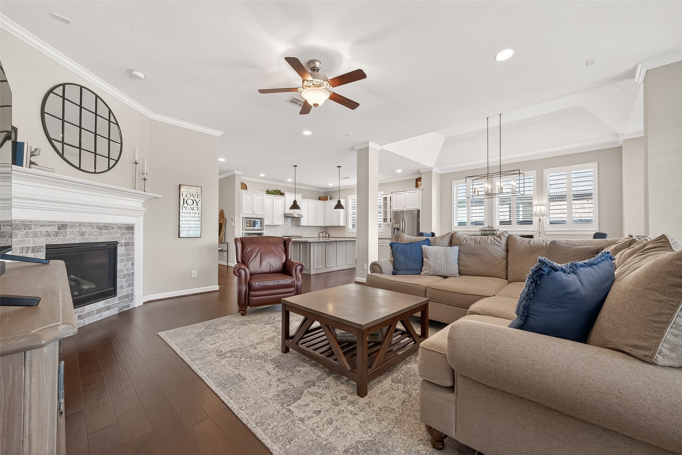 1307 Layla Sage Loop Richmond, TX 77406 - Photo 24 of 50 The family room features a wall of windows overlooking the backyard and tranquil lake view, anchored by a corner wood-burning fireplace with brick surround and wood mantle creating a warm, inviting atmosphere for gatherings and cozy evenings.
