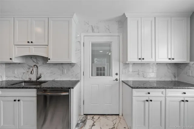 a kitchen with granite countertop white cabinets and stainless steel appliances