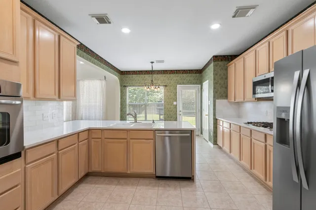 a large kitchen with stainless steel appliances granite countertop a refrigerator a sink dishwasher a stove and white countertops with cabinets