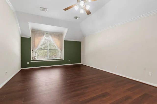 an empty room with wooden floor chandelier and windows