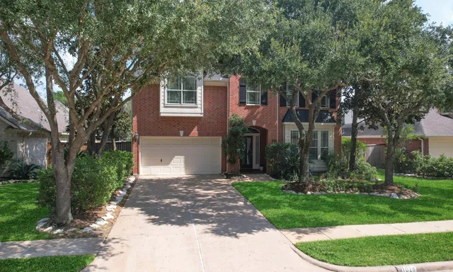 front view of a house with a yard and an trees