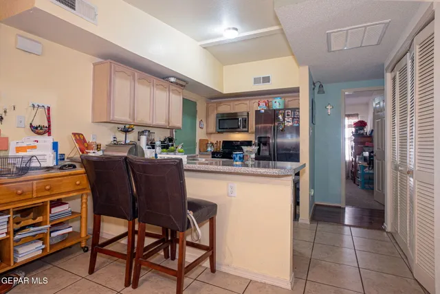 a kitchen with stainless steel appliances granite countertop a table chairs and a refrigerator