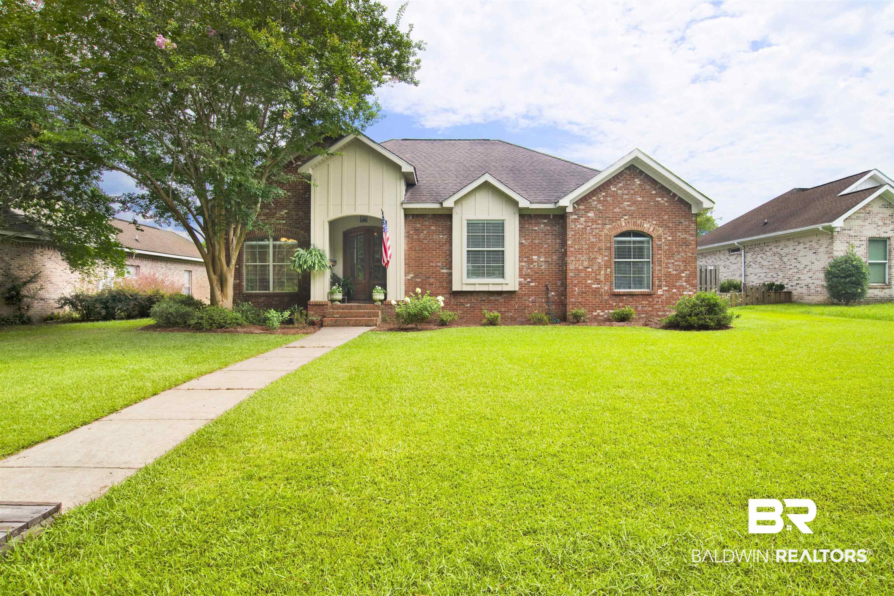 10368 Gayfer Rd Extension Fairhope, AL 36532 - Photo 1 of 43 Brick exterior with white vertical siding accents, a dark shingle roof, and a mature front yard tree