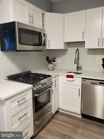 a kitchen with cabinets stainless steel appliances and wooden floor