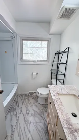 a bathroom with a granite countertop sink a toilet and a window