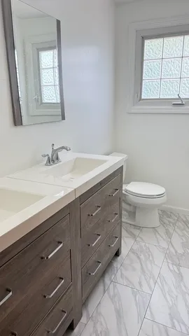 a bathroom with a granite countertop toilet sink and mirror