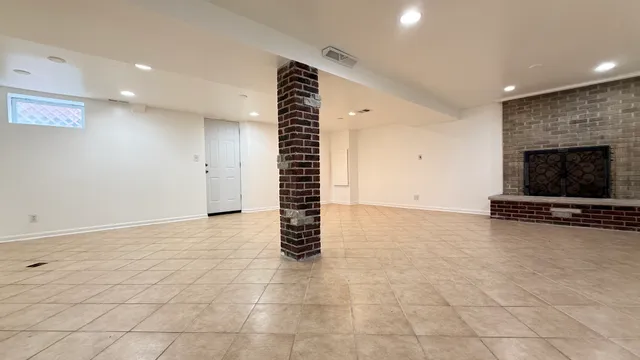 a view of an empty room with a fireplace and a window