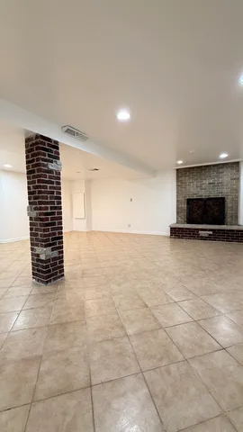 a view of an empty room with kitchen and a window