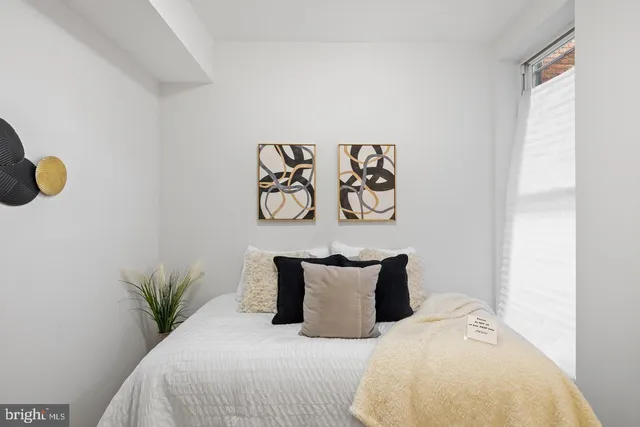 a bed sitting in a bedroom next to a window with painting on the wall