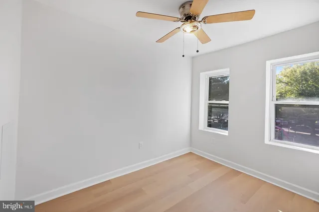 an empty room with a window and a fan