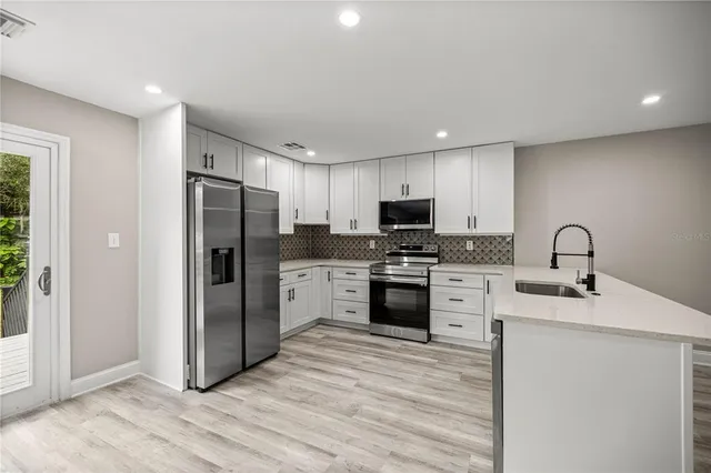 a kitchen with refrigerator a sink and a stove top oven with wooden floor