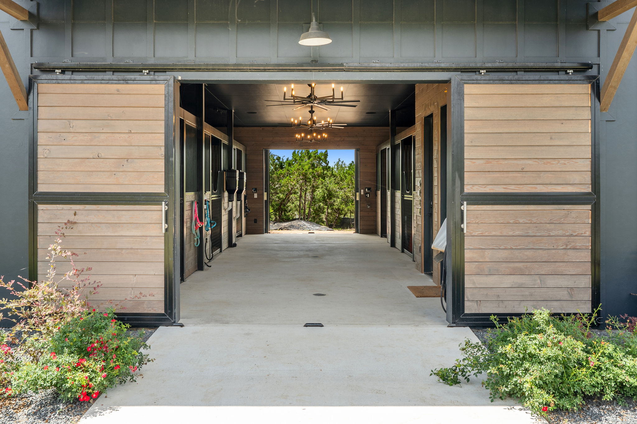 475 Happy Trail Dripping Springs, TX 78620 - Photo 37 of 40 A refined stable with modern light fixtures and concrete flooring, framed by mature trees.