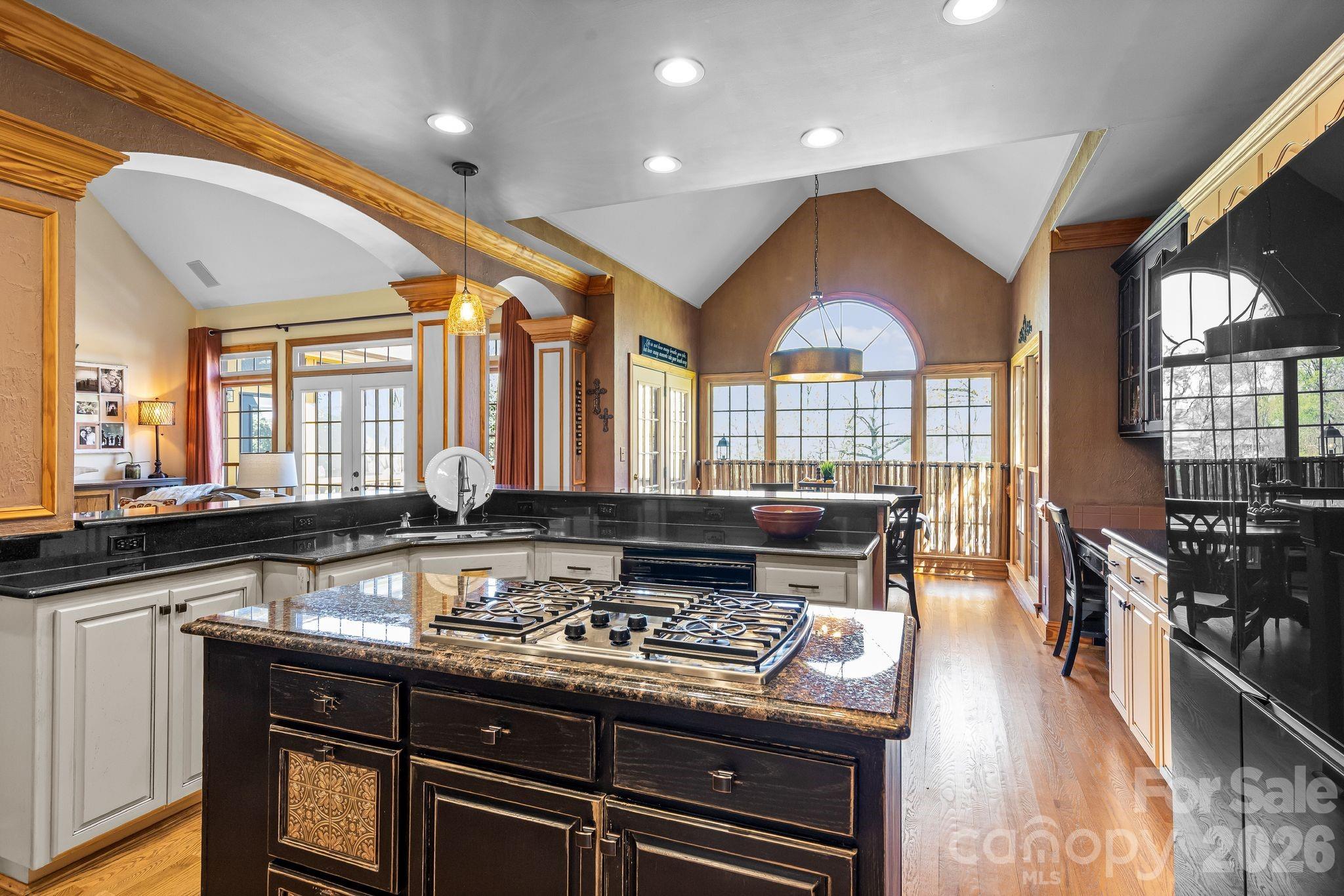 3530 Cardiff Lane Matthews, NC 28104 - Photo 20 of 39 a kitchen with a stove a sink a dining table and chairs with wooden floor