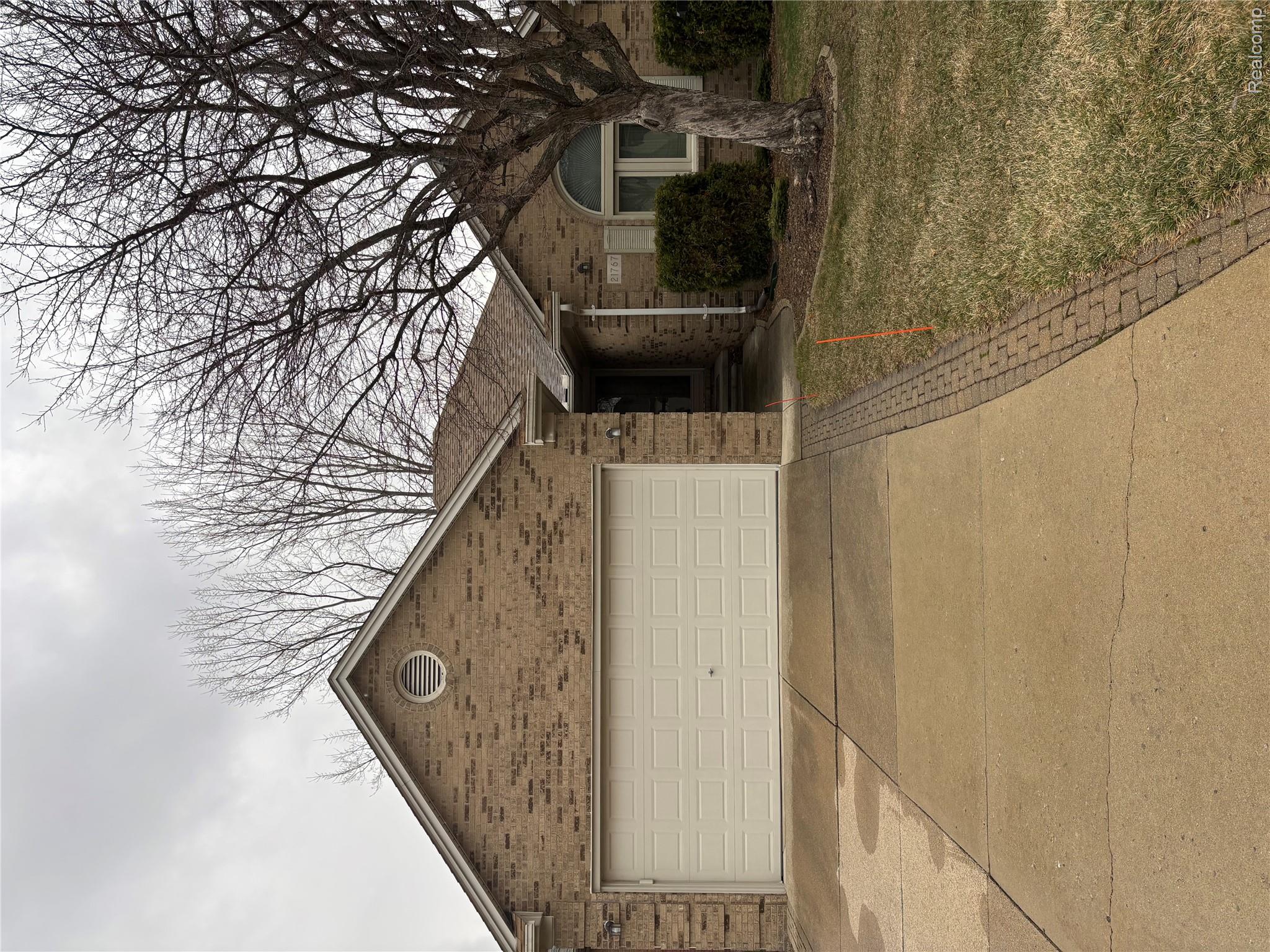 21767 Sunset Drive, Unit 25 Macomb, MI 48044 - Photo 1 of 13 View of front facade with concrete driveway, brick siding, a garage, and a front lawn