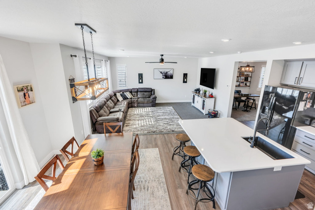 252 North Sunrise Rnch Drive Mapleton, UT 84664 - Photo 23 of 62 Open-concept dining and living area featuring wood-finish flooring, a contemporary island with an undermount sink, a linear chandelier, and recessed lighting