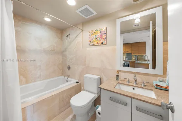 a bathroom with a granite countertop sink toilet and painting on the wall
