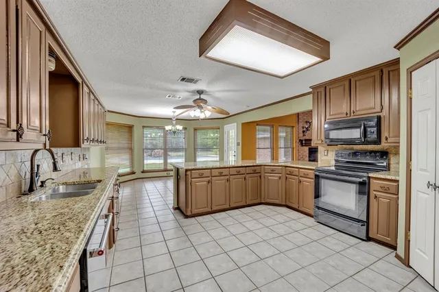 a large kitchen with granite countertop a large stove top oven and cabinets