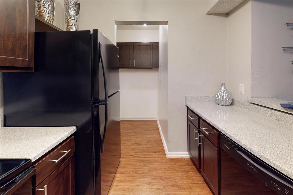 1826 Esters Road, Unit 1050 Irving, TX 75061 - Photo 8 of 39 Kitchen featuring wood-finish flooring, dark wood-finish cabinetry, light speckled countertops, and black appliances