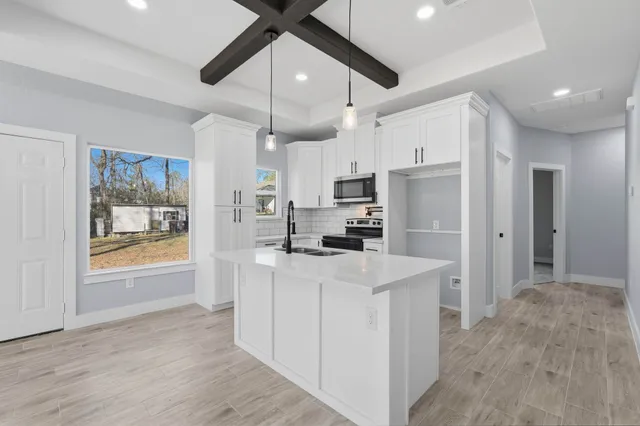 a kitchen view with stainless steel appliances a refrigerator a stove a sink a center island a stove and a center island