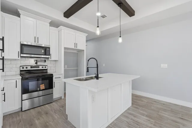 a kitchen with stainless steel appliances a stove a sink and white cabinets